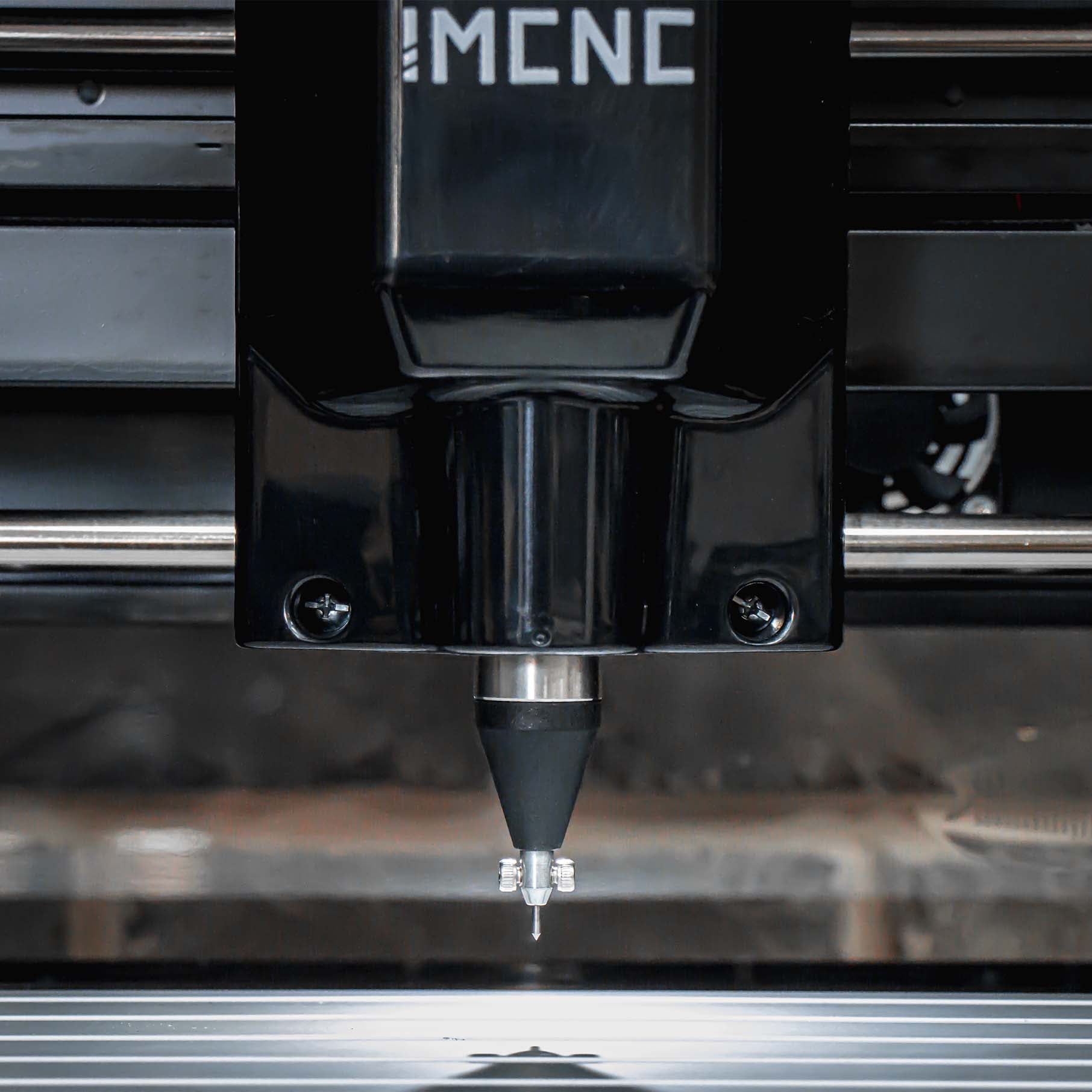 Close-up of IMCNC mini CNC spindle with impact dot peen installed, positioned above aluminum engraving bed.