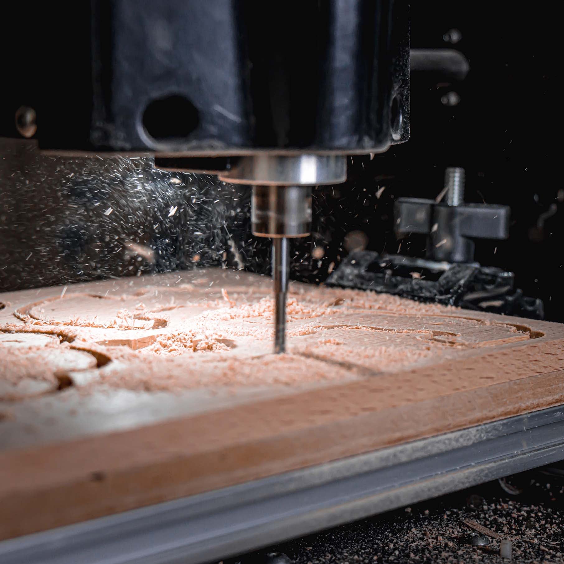 IMCNC mini CNC engraving machine in action, cutting detailed patterns into wood with spindle rotating, wood shavings flying.