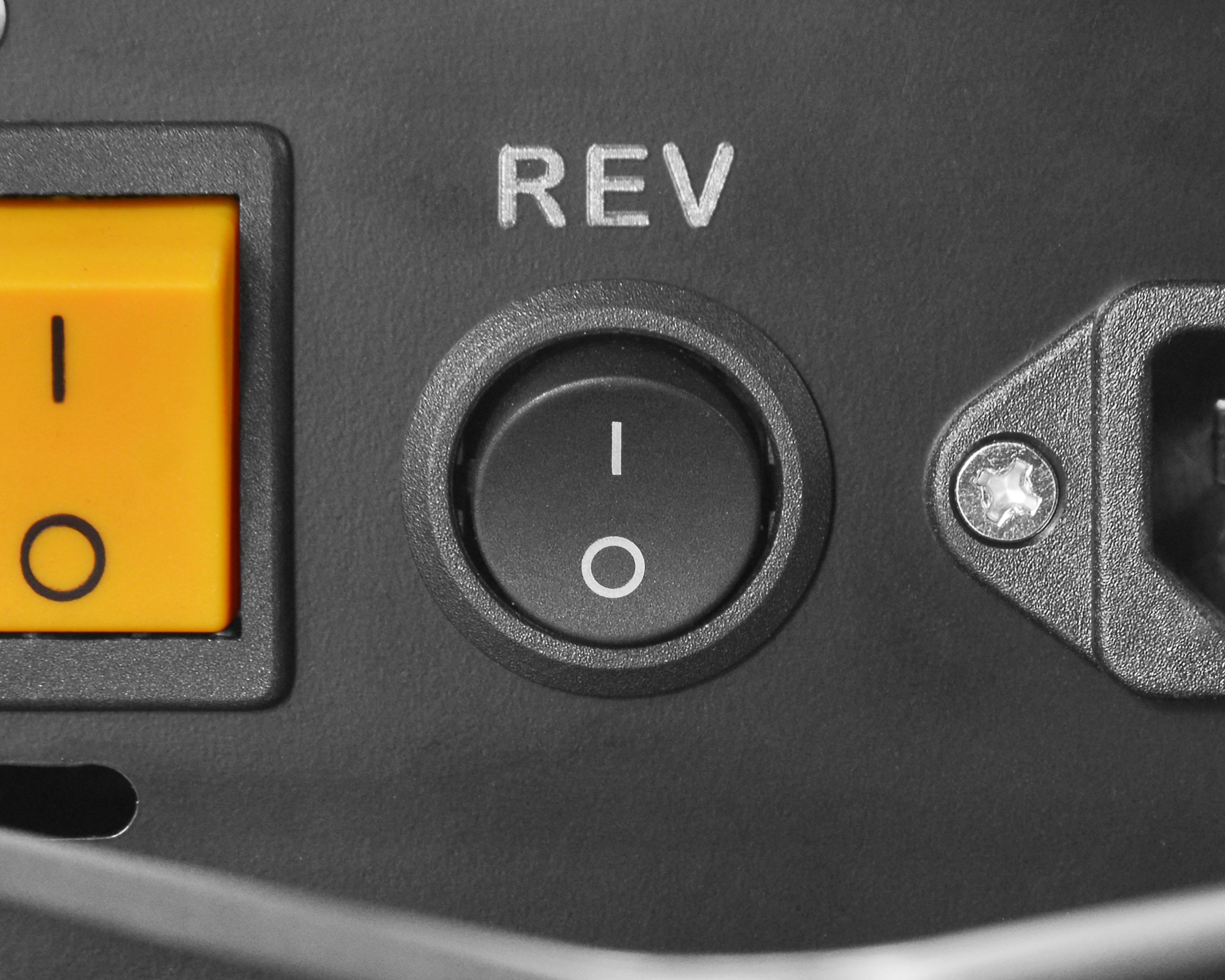 A close-up of a rotary power tool’s control panel showing a REV switch with ON and OFF positions.