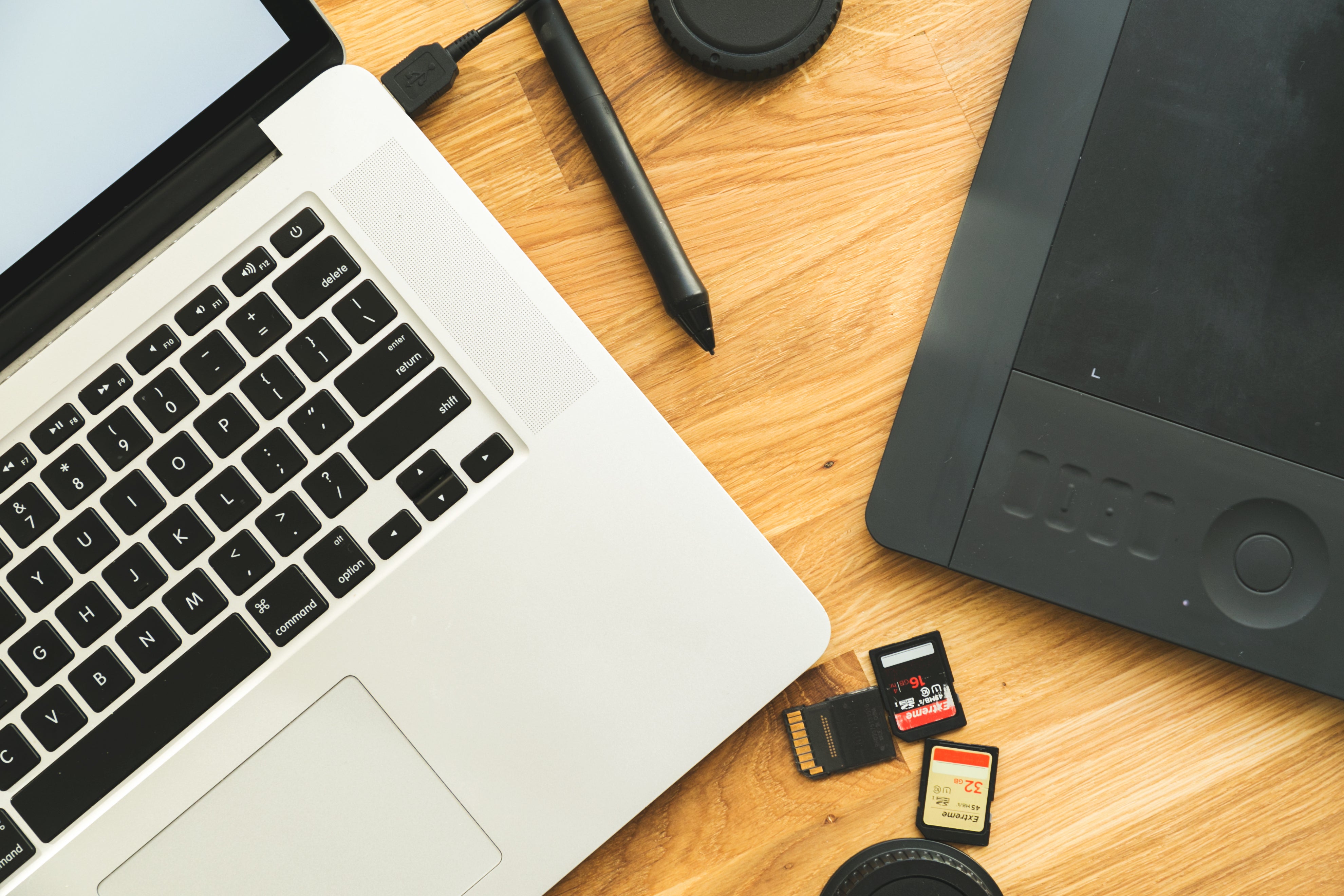 Workspace flat lay with laptop, graphic tablet, SD cards, and accessories, used webpage design,